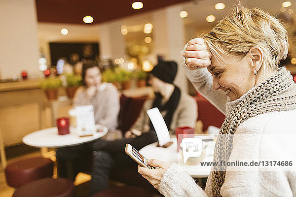Junge glückliche Frau benutzt Smartphone in einem Cafe