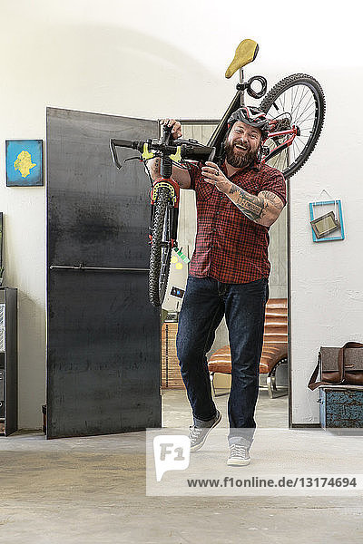 Porträt eines lachenden Mannes mit Fahrrad im Büro