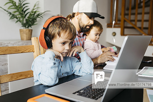 Father working at home  using laptop with his children on his lap