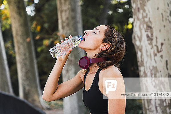 Fitte junge Frau macht eine Pause  trinkt Wasser