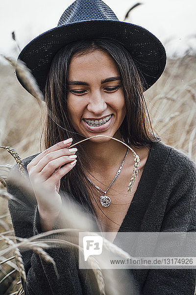 Portrait of laughing young woman dressed in black in a corn field