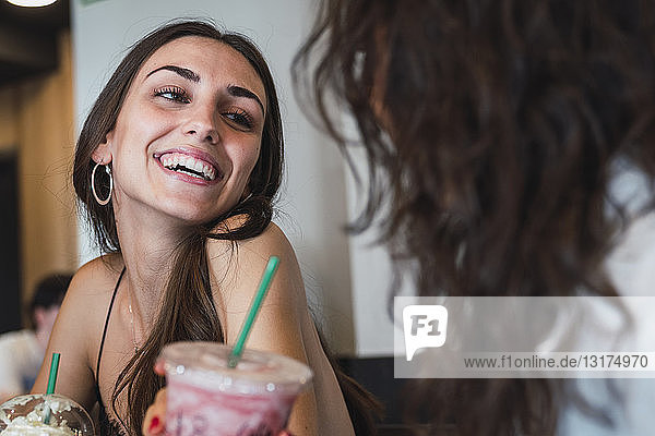 Portrait of happy young woman in a coffee shop having fun with her friend
