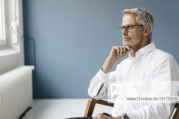 Manager sitting in chair in his office  looking out of the window  thinking