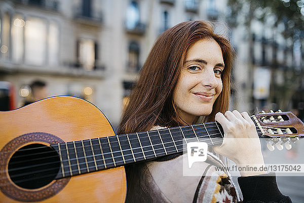 Rothaarige Frau mit Gitarre in der Stadt