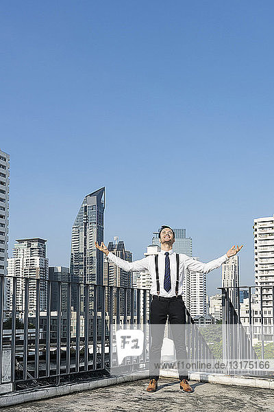Happy and content successful business man on city rooftop