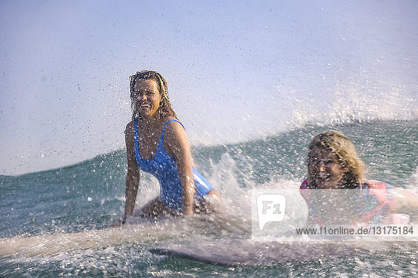 Indonesia  Bali  Batubolong beach  young female surfers on board  splash water