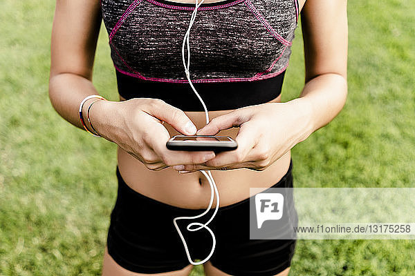 Teenage girl using smartphone and earphone on race track