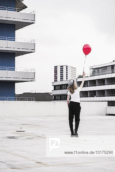 Rückenansicht einer jungen Frau mit rotem Ballon
