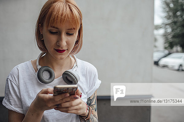 Young woman with headphones using cell phone