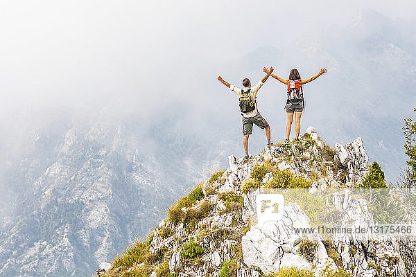 Italy  Massa  happy couple cheering on top of a peak in the Alpi Apuane mountains