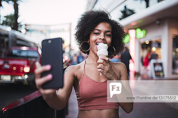 USA,  Nevada,  Las Vegas,  glückliche junge Frau beim Eisessen in der Stadt,  die ein Selfie nimmt