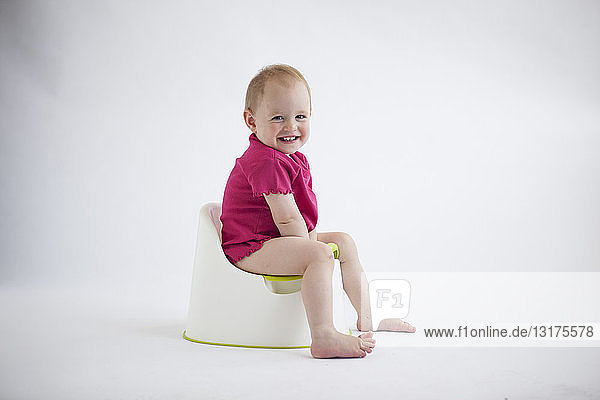 Porträt eines lachenden Mädchens  das auf dem Töpfchen sitzt