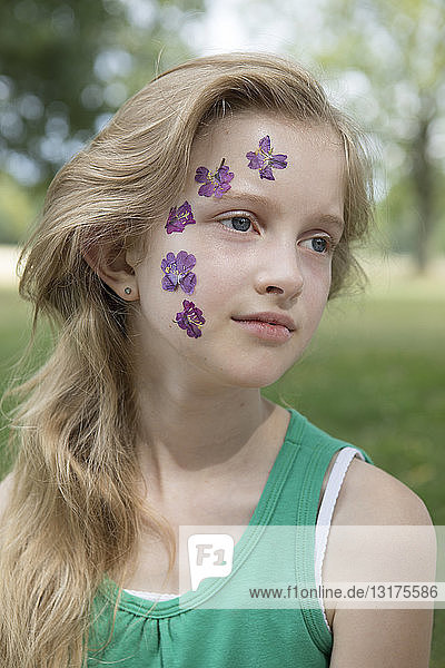 Bildnis eines blonden Mädchens mit einer Tätowierung aus gepressten Blumen im Gesicht
