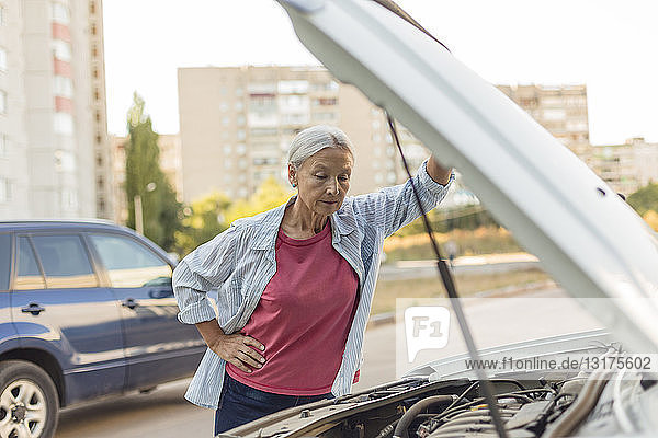 Ältere Frau betrachtet Automotor