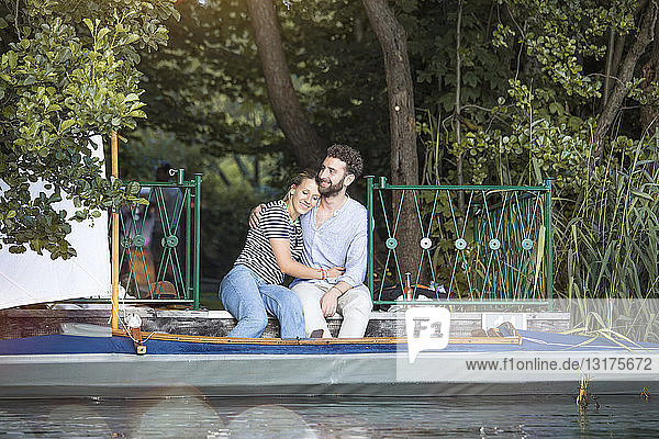Glückliches junges Paar mit Kanu auf einem Steg sitzend