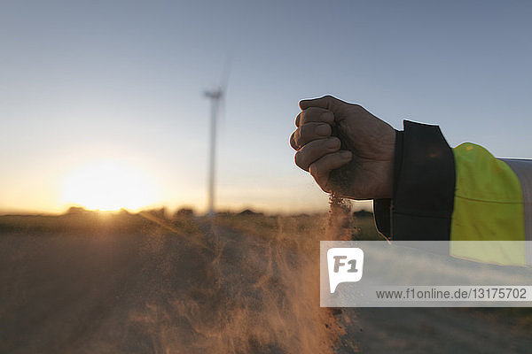 Nahaufnahme der von Menschenhand verstreuten Erde an einer Windkraftanlage bei Sonnenuntergang