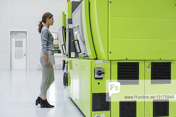 Geschäftsfrau in einem High-Tech-Unternehmen  das Produktionsmaschinen kontrolliert