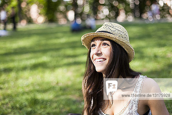 Porträt einer glücklichen jungen Frau in einem Park  die etwas beobachtet