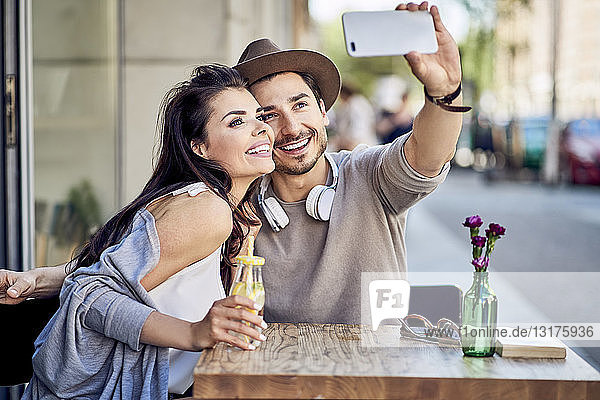 Happy young couple taking a selfie at outdoors cafe