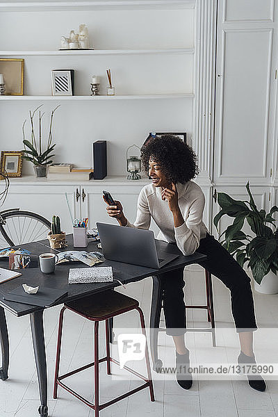 Mid adult woman working in her home office  using smartphone