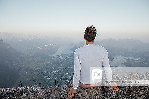Switzerland  Grosser Mythen  young man on a hiking trip sitting on a rock at sunrise