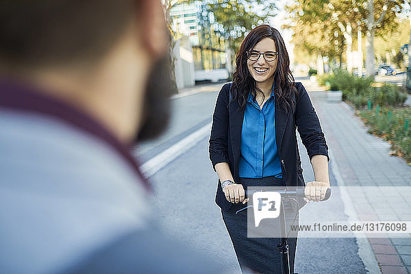 Smling businesswoman with scooter meeting businessman