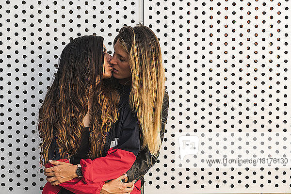 Lesbisches Paar küsst sich an einer Wand