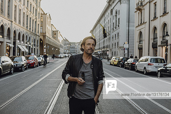 Man wearing leather jacket walking in the street  Munich  Germany