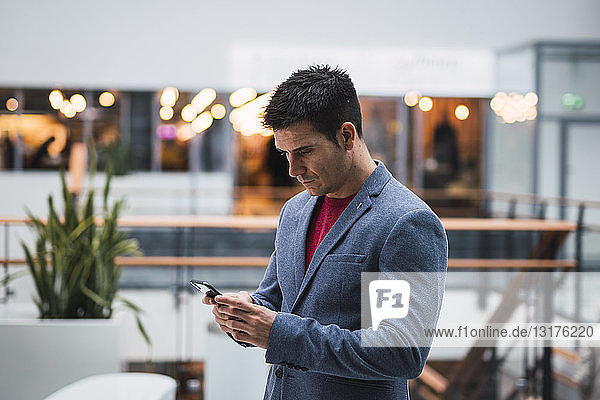 Businessman in lobby of a modern building  using smartphone