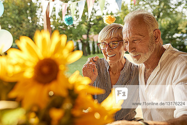 Glückliches älteres Ehepaar umarmt sich auf einer Gartenparty