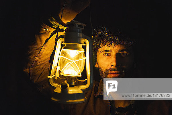 Portrait of man holding storm lantern in the dark