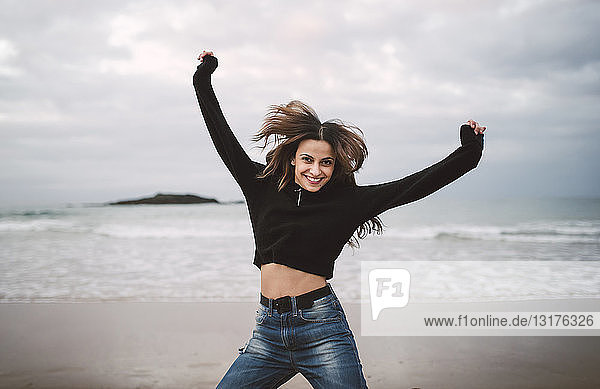 Portrait of happy young woman jumping on the beach