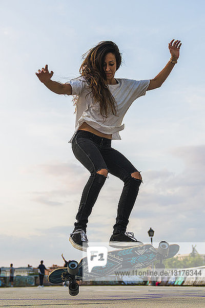 Junge Frau bei einem Skateboardtrick in der Stadt