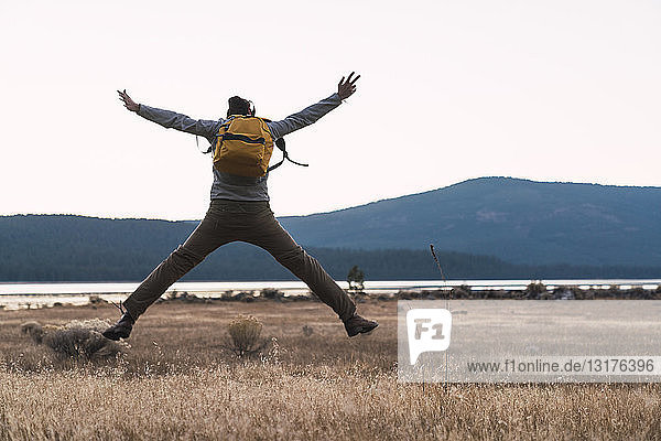 USA  North California  rear view of young man on a hiking trip jumping near Lassen Volcanic National Park