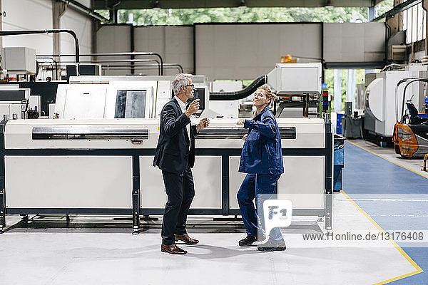Manager and skilled worker dancing in factory workshop  having fun