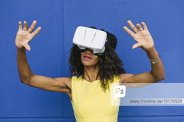 Frau mit Virtual-Reality-Brille vor blauem Hintergrund