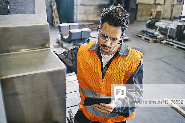 Mann mit Tablette in Arbeitsschutzkleidung bei der Arbeit in der Fabrik