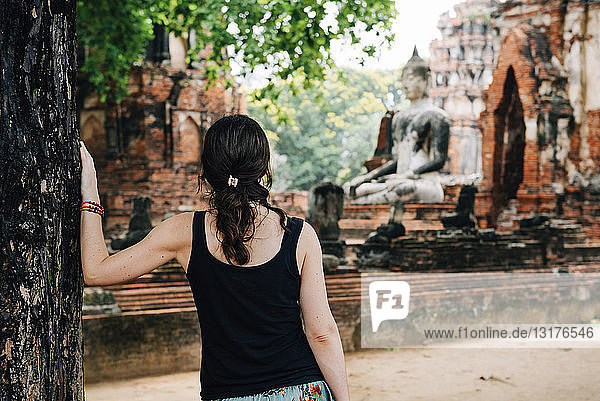 Thailand  Ayutthaya  Frau betrachtet eine Buddhastatue im Wat Mahathat