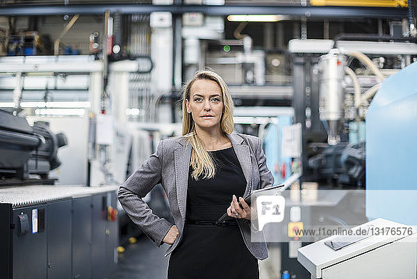 Portrait of confident woman holding tablet in factory shop floor