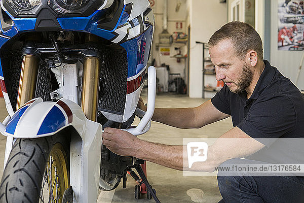 Mechaniker  der in der Werkstatt am Motorrad arbeitet