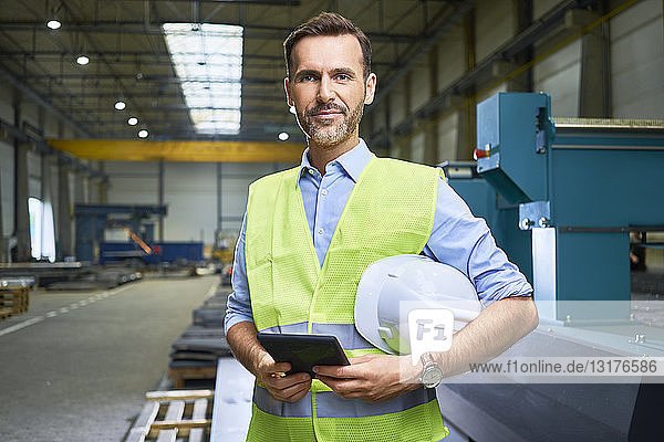 Porträt eines selbstbewussten Mannes mit Hemd und Sicherheitsweste in der Fabrik
