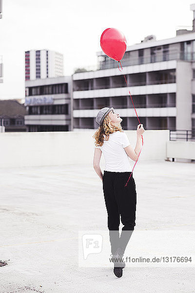 Rückenansicht einer jungen Frau mit rotem Ballon