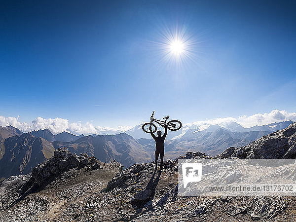 Grenzregion Italien Schweiz  jubelnder Mann mit Mountainbike auf dem Gipfel des Piz Umbrail