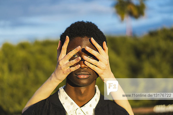 Hände bedecken die Augen eines jungen schwarzen Mannes