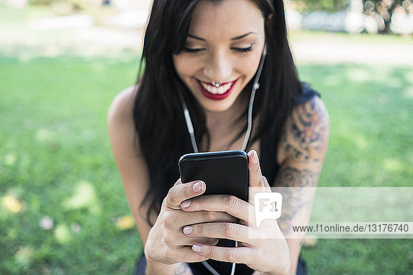 Lächelnde junge Frau hält Smartphone in den Händen