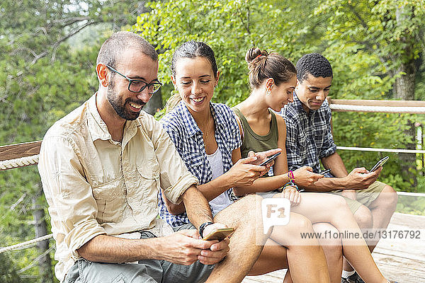 Italy  Massa  hikers in the Alpi Apuane mountains looking at their smartphones and sitting on a bench