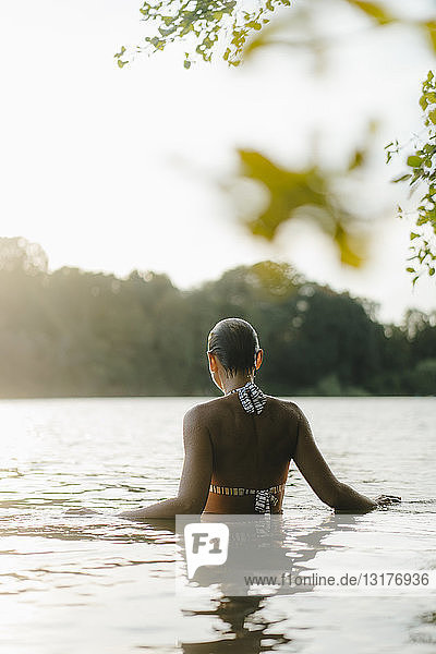 Rückansicht einer Frau in einem See bei Sonnenuntergang