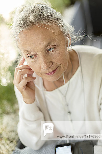Porträt einer älteren Frau mit Mobiltelefon und Kopfhörern