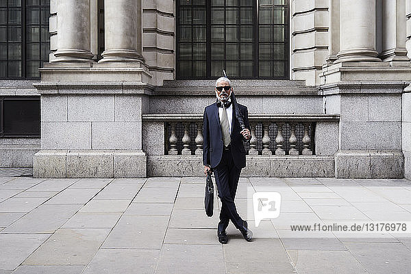 Großbritannien  London  Porträt eines stilvollen Geschäftsmannes mit Sonnenbrille und Regenschirm in Anzug und Krawatte