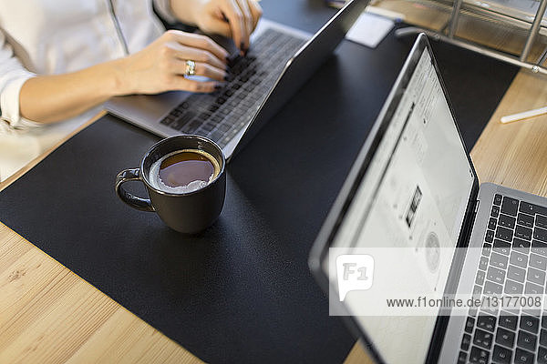 Close-up of woman using laptop at desk in office